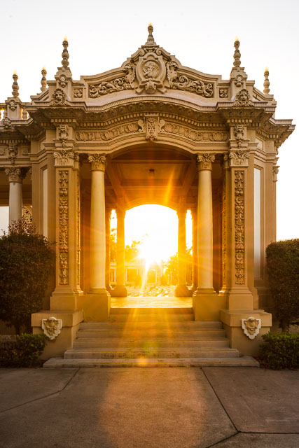 Archway at the Spreckels Organ Pavilion in Balboa Park. The sun is setting right in the center throwing off beautiful sun rays.